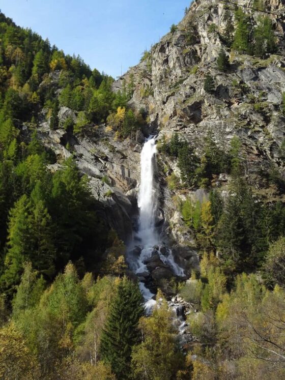 Une cascade dans les montagnes entourée d'arbres.