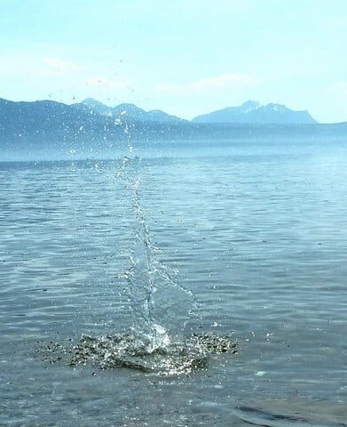 Eau éclaboussant d'un plan d'eau avec des montagnes en arrière-plan.