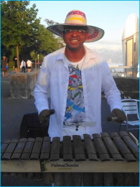 Un homme portant un chapeau et un chapeau joue du xylophone.