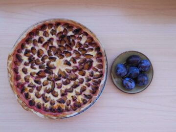 Une tarte aux prunes et une assiette à côté.