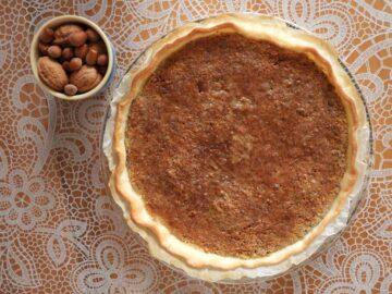 Une tarte est posée sur une table à côté d’un bol de noix.