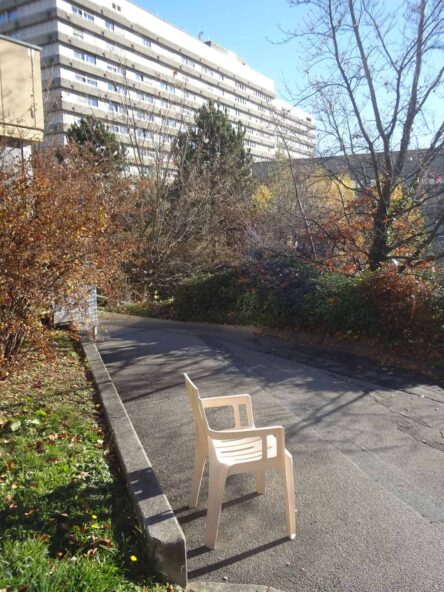 Une chaise posée sur un trottoir devant un immeuble.