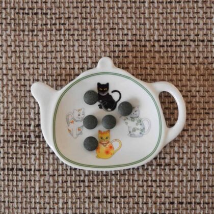 Une théière avec des chats noirs dessus.