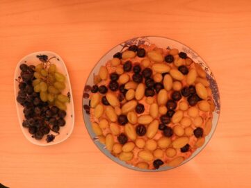 Une assiette de fruits et un bol de raisins.