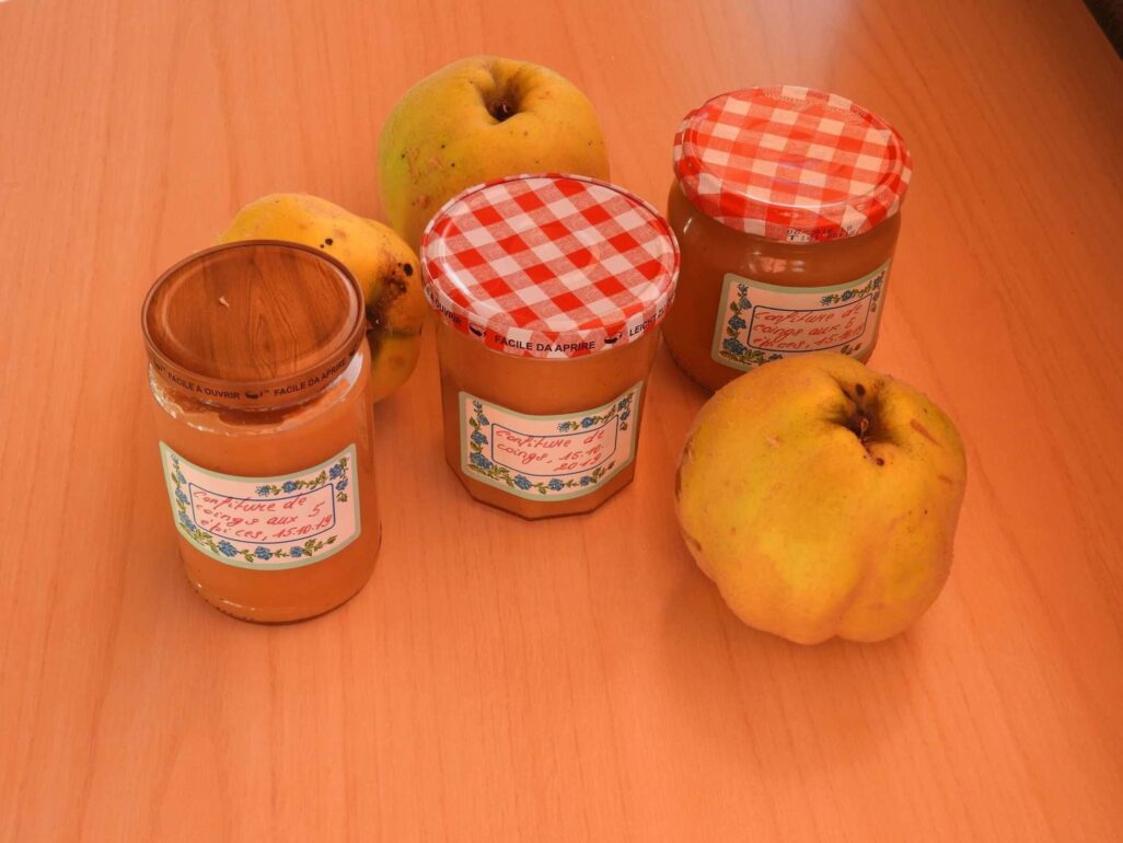 Quatre pots de confiture de pommes sur une table en bois.
