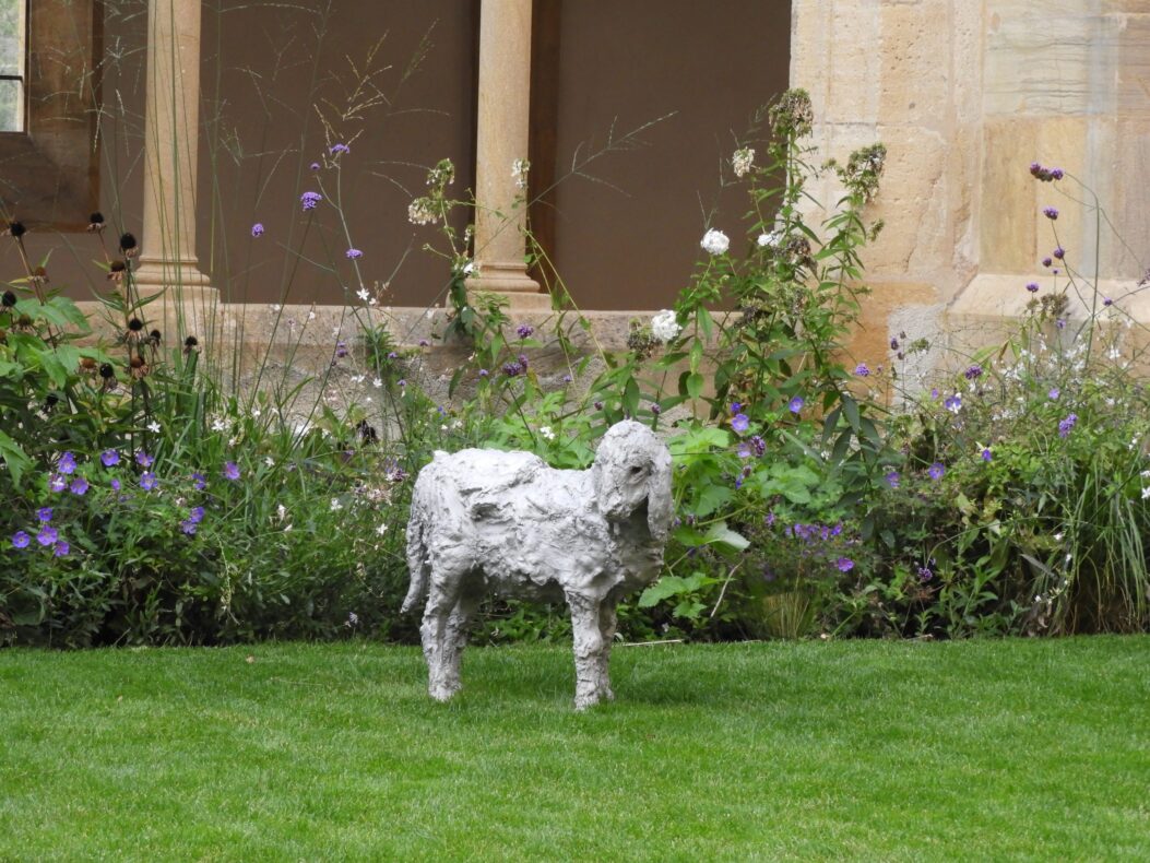 Une statue d'un mouton dans un jardin.