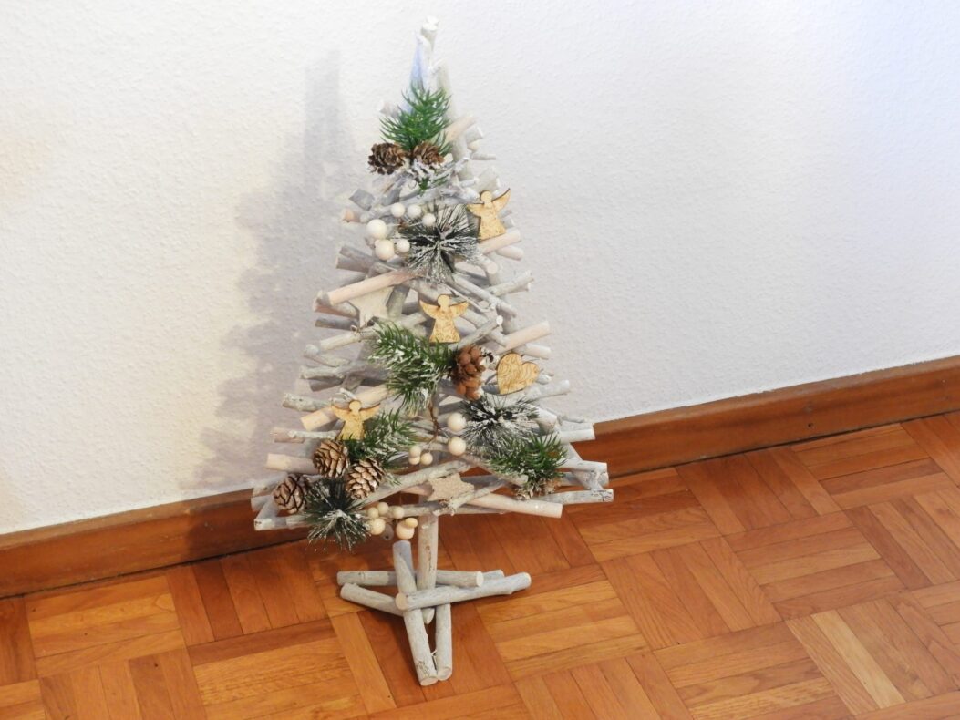 Un petit sapin de Noël composé de brindilles sur un parquet.
