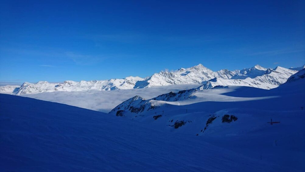 Un ciel bleu avec des montagnes enneigées en arrière-plan.