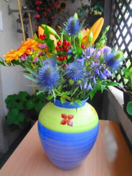 Un vase de fleurs devant une fenêtre.