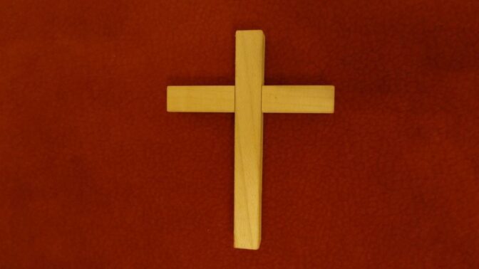 Une croix en bois sur fond rouge.