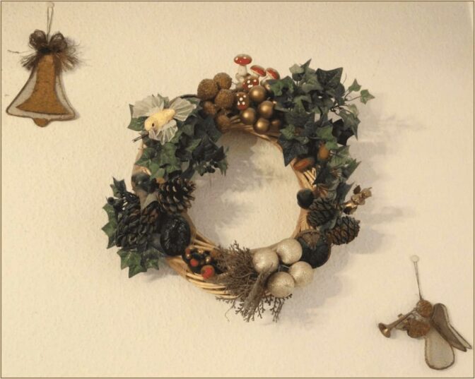 Une couronne accrochée au mur, ornée de clochettes et de lierre, symbolisant Noël.