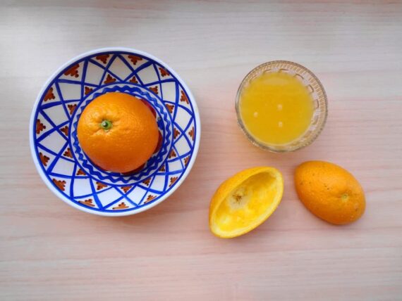 Un bol de jus d'orange à côté d'un bol d'oranges.