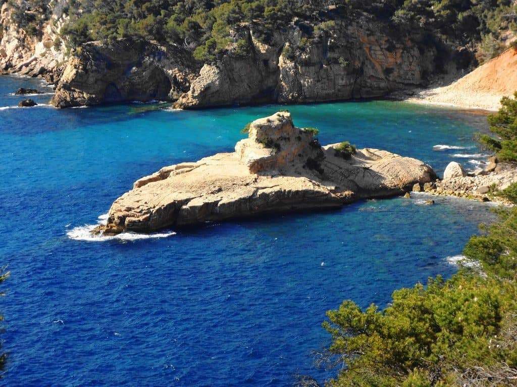 Une petite île entourée d'eau bleue et d'un rivage rocheux, avec un sous-marin et un distributeur automatique.